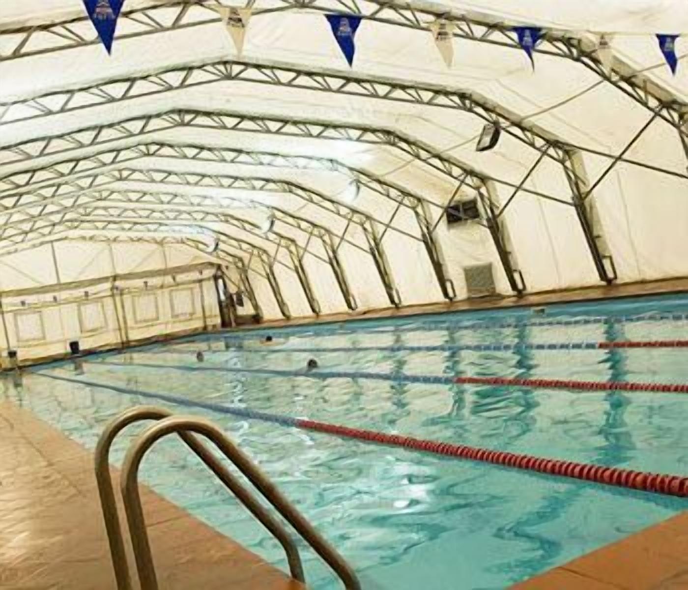 Une piscine intérieure avec des couloirs bien délimités et une structure de toit en métal.