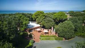 Ein geräumiges, modernes Haus mit großzügiger Terrasse, umgeben von üppiger Vegetation und Blick aufs Meer.