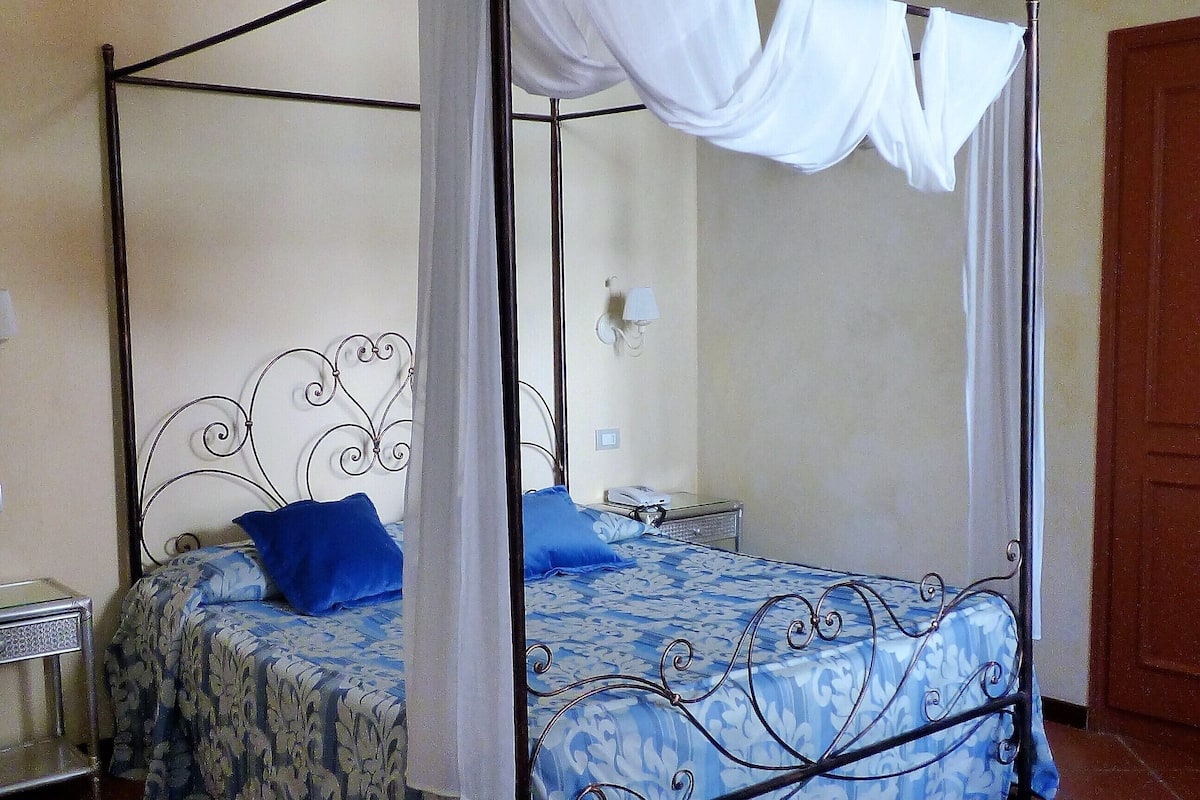 A four-poster bed with a canopy, two bedside tables, and a nightstand.