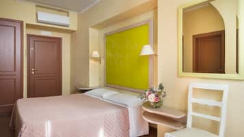 A hotel room with a bed, a desk, a chair, a mirror, and a window with a view.