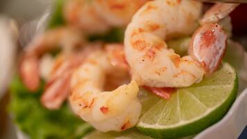 A bowl of shrimp on a bed of lettuce with a slice of lime.