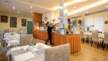 Un ristorante con diversi tavoli, un'area bar centrale e varie decorazioni alle pareti.