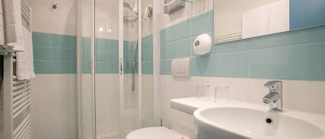 A bathroom with a glass-enclosed shower, a white toilet, and a sink with a mirror above it.