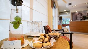 Una mesa con un vaso de té helado, un plato de pasteles y una tarjeta de presentación de hotel.