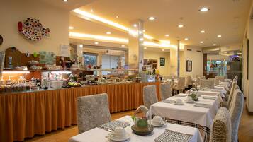A buffet-style dining area with multiple tables and chairs, a central serving station, and a variety of food and drink options.