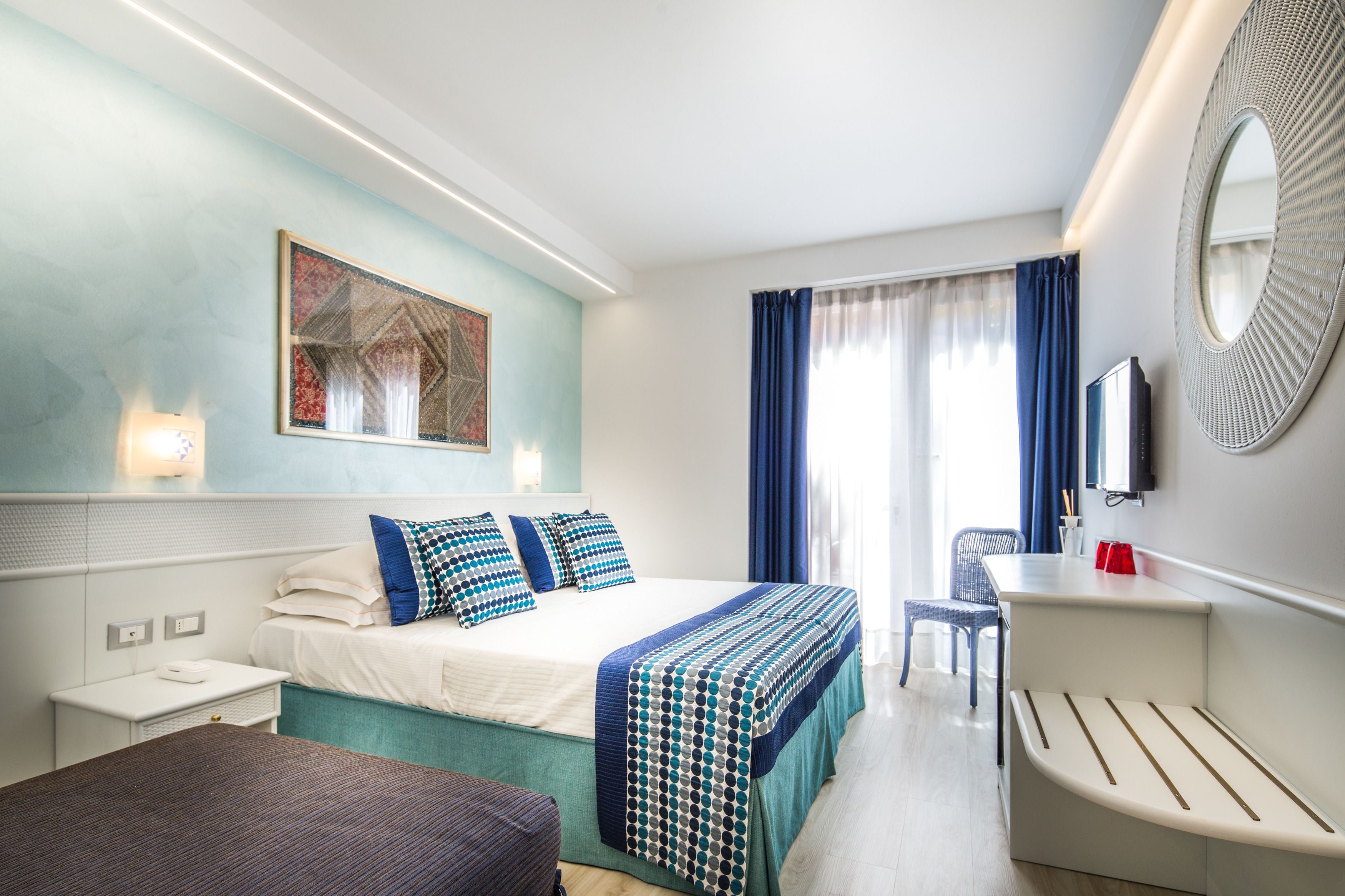 A hotel room with a bed, bedside table, chair, and a TV.