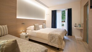 Una habitación de hotel moderna con una cama grande, una cama individual, una mesita de noche, un estante empotrado y un ventanal con cortinas.