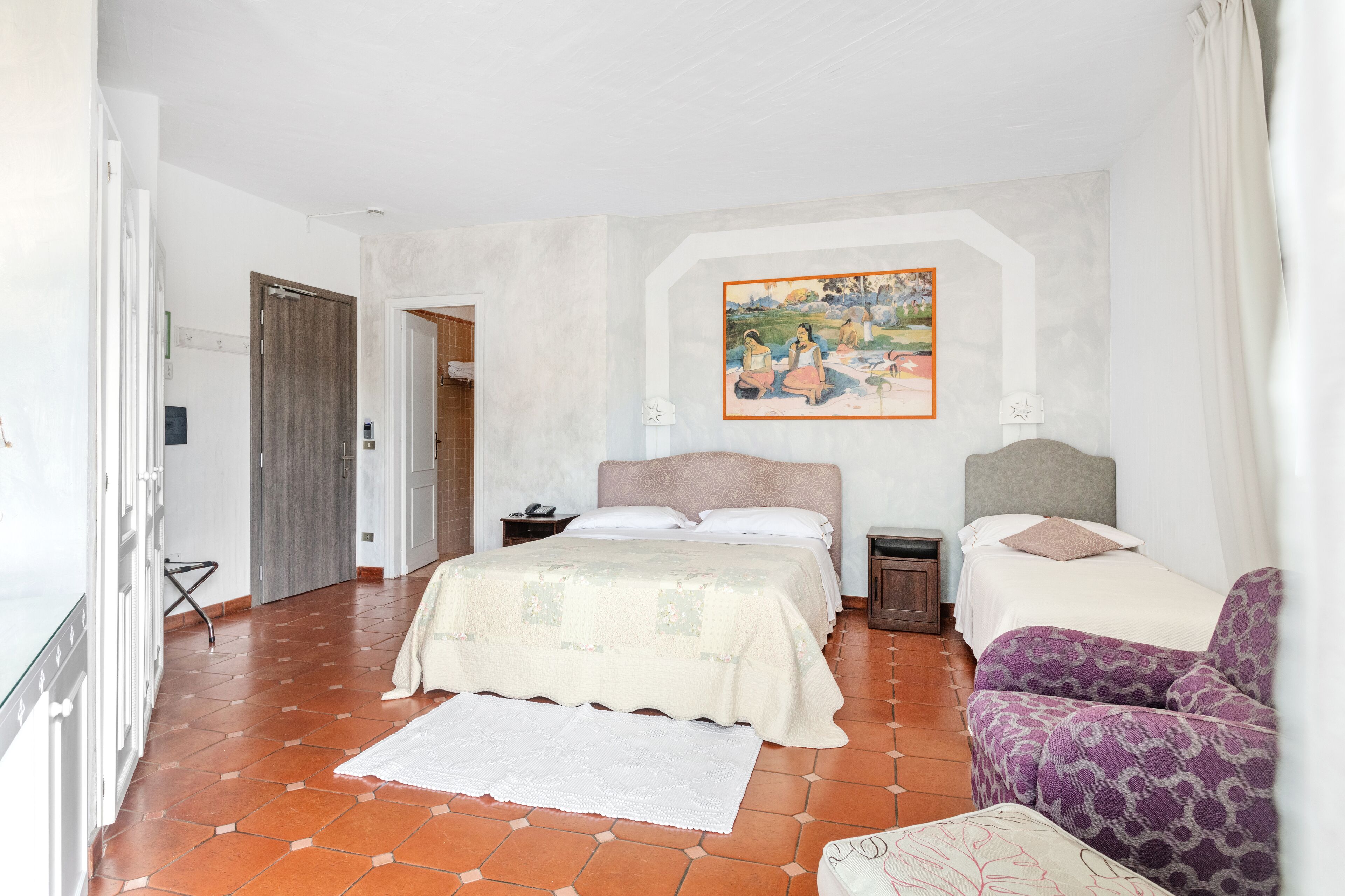 A bedroom with a large bed, two bedside tables, a chair, a painting on the wall, and a door leading to another room.