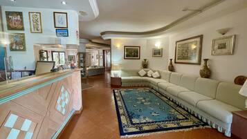 A spacious lobby with a reception desk, a large beige sofa, and a patterned rug.