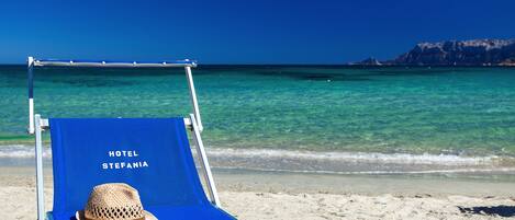 Plage, sable blanc, chaises longues, parasols