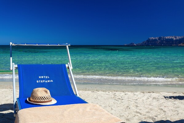 على الشاطئ، رمال بيضاء، كراسي للتشمس، مظلات الشاطئ