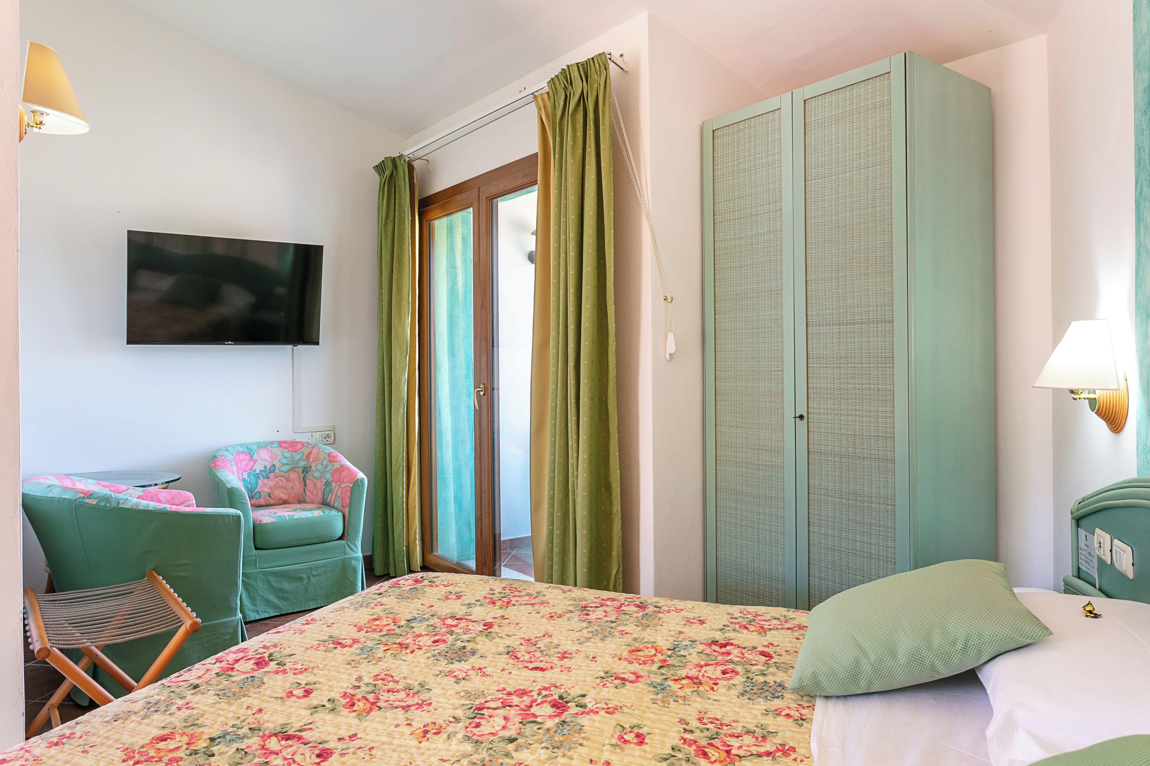 Ein Schlafzimmer mit Bett, Stuhl, Fernseher und Kleiderschrank.