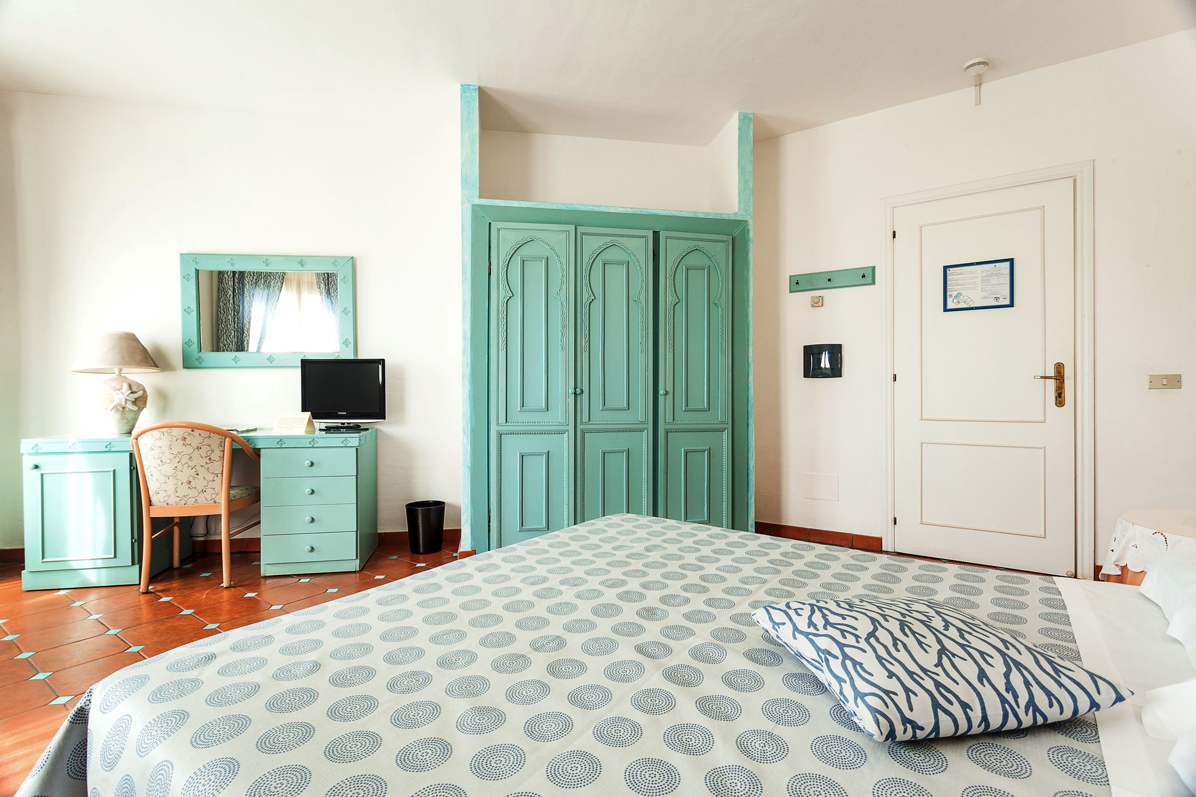 A bedroom with a bed, a desk, a chair, and a wardrobe.