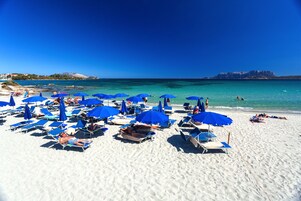 On the beach, white sand, sun loungers, beach umbrellas