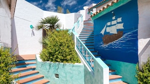 Una escalera con barandillas y escalones turquesa, que conduce a un edificio con un mural de un barco en la pared.