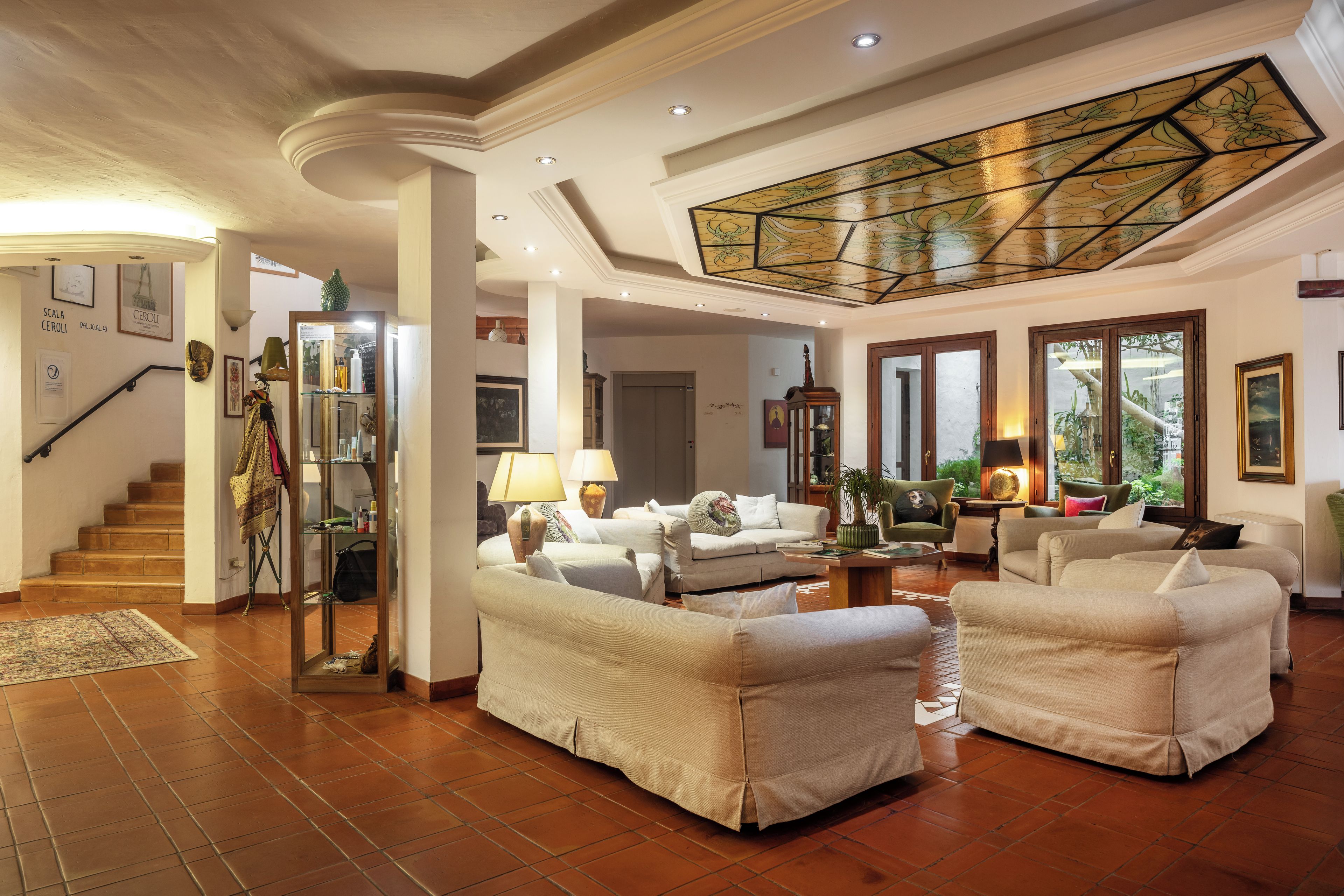 A spacious living room with a high ceiling, a staircase, and a conservatory with a stained glass ceiling.