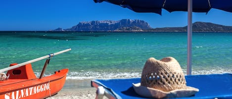 On the beach, white sand, sun-loungers, beach umbrellas