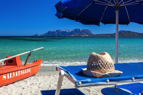 På stranden, vit sandstrand, solstolar och parasoller