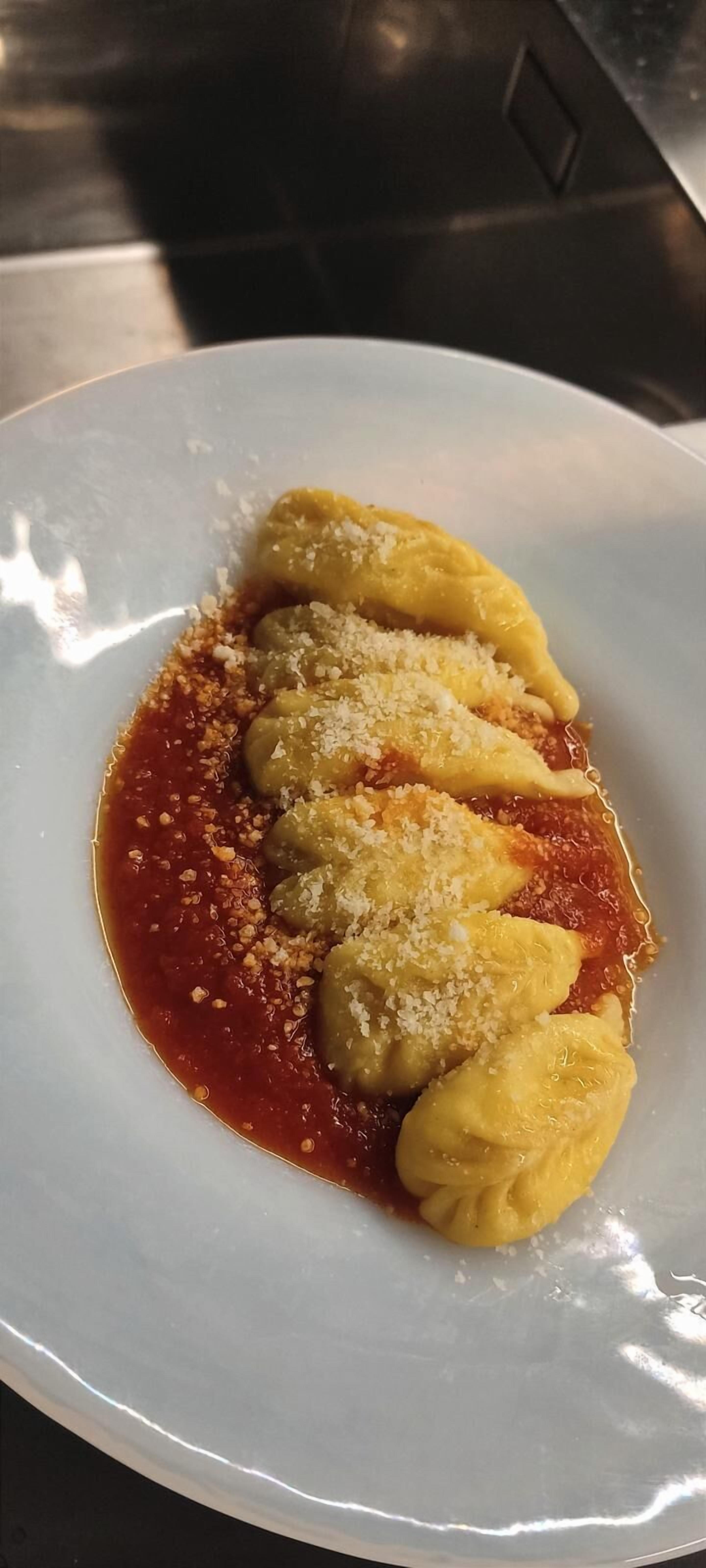 En tallrik ravioli med tomatsås och riven ost.