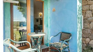 Un patio con mobiliario de mimbre, una mesa y un muro de piedra.