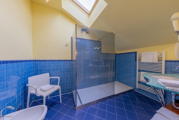 A bathroom with a glass-enclosed shower, a white chair, a bathtub, and a glass sink. - La Darsena Boutique Hotel & Restaurant (Tremezzina)