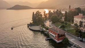 A waterfront hotel with a red building, a clock tower, and a view of the lake and mountains. - La Darsena Boutique Hotel & Restaurant (Tremezzina)