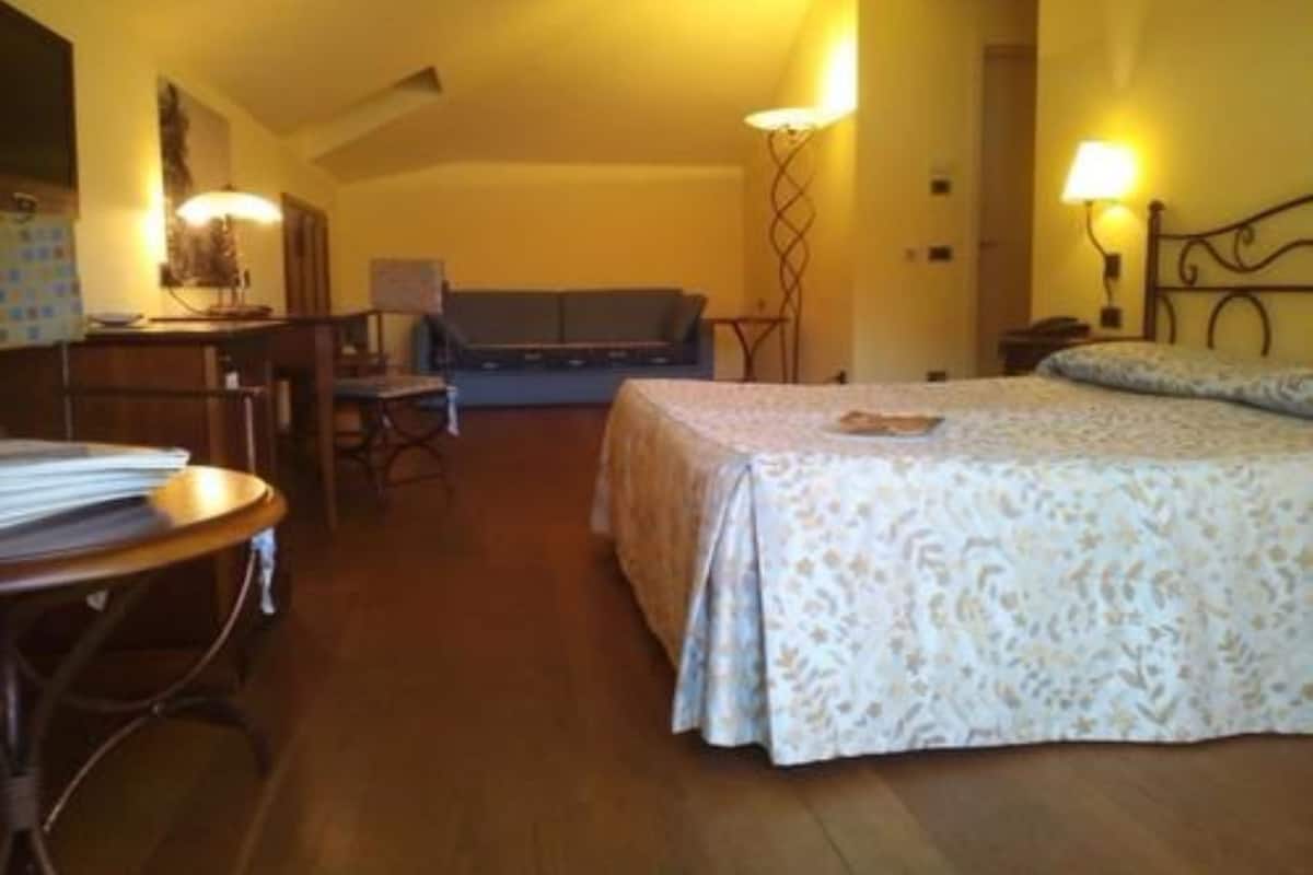 Habitación de hotel con cama, escritorio, silla y sofá.