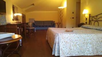 A hotel room with a bed, a desk, a chair, and a sofa.