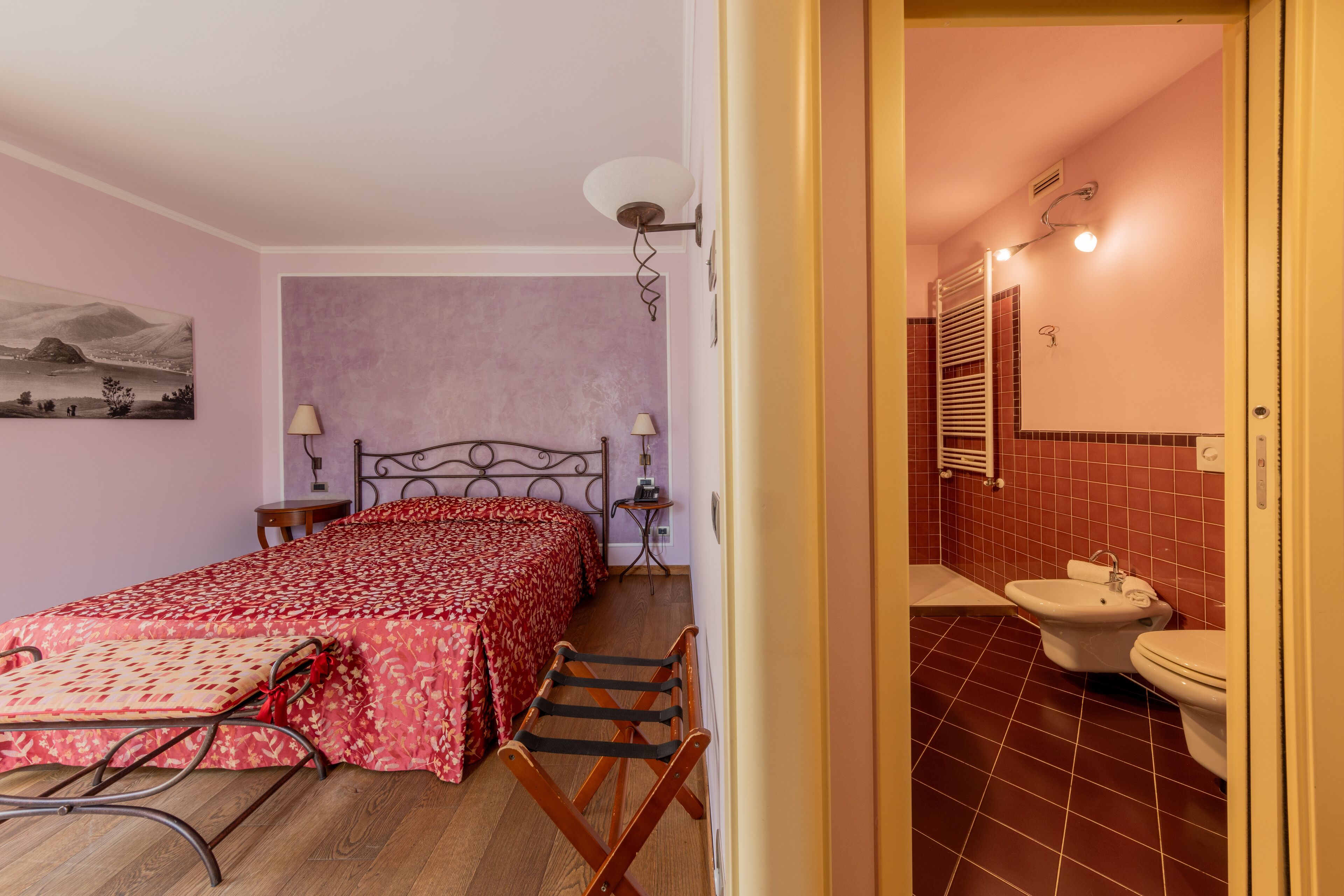 A bedroom with a bed, bedside tables, a lamp, and a painting on the wall.