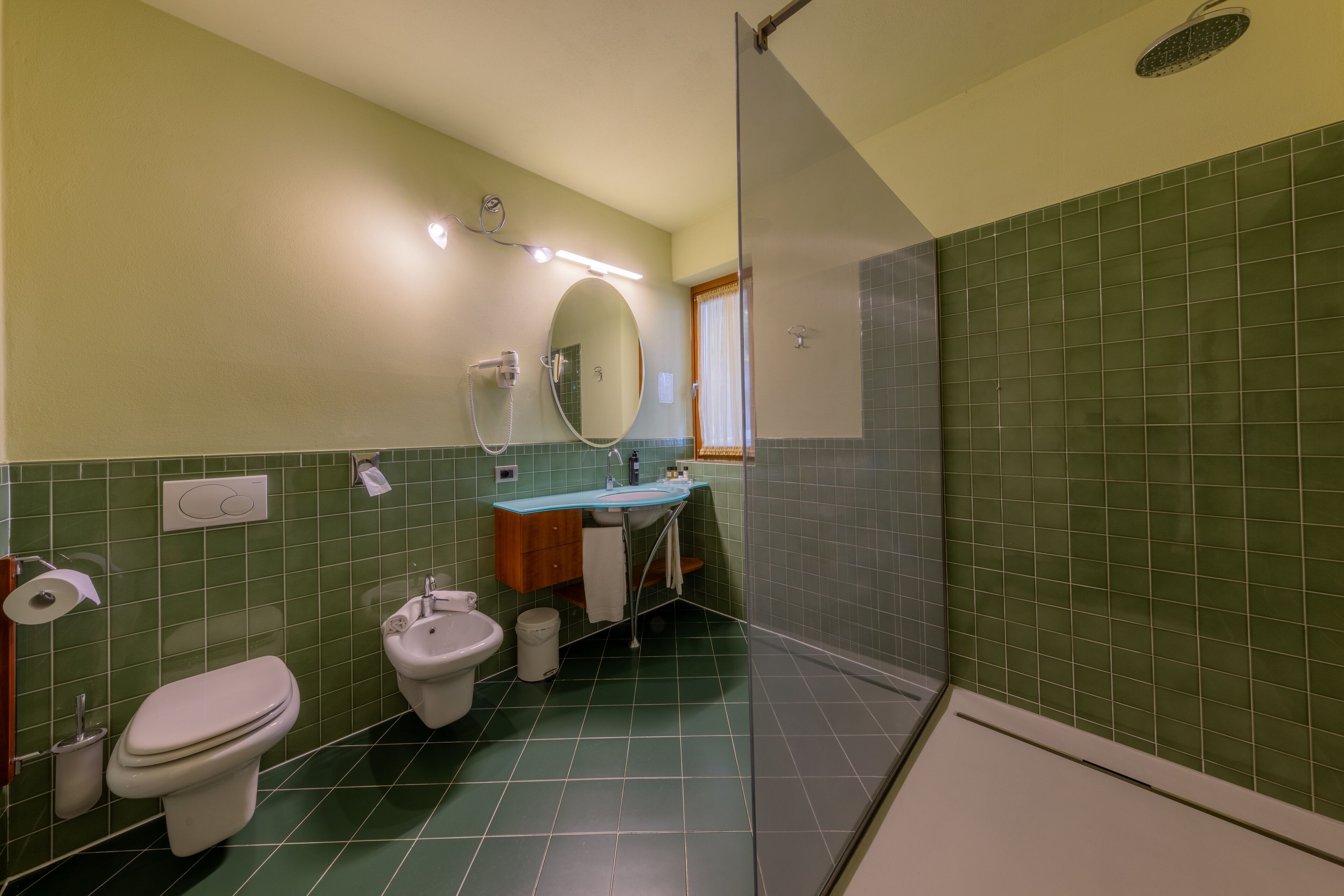 A bathroom with a toilet, bidet, sink, and a shower area.