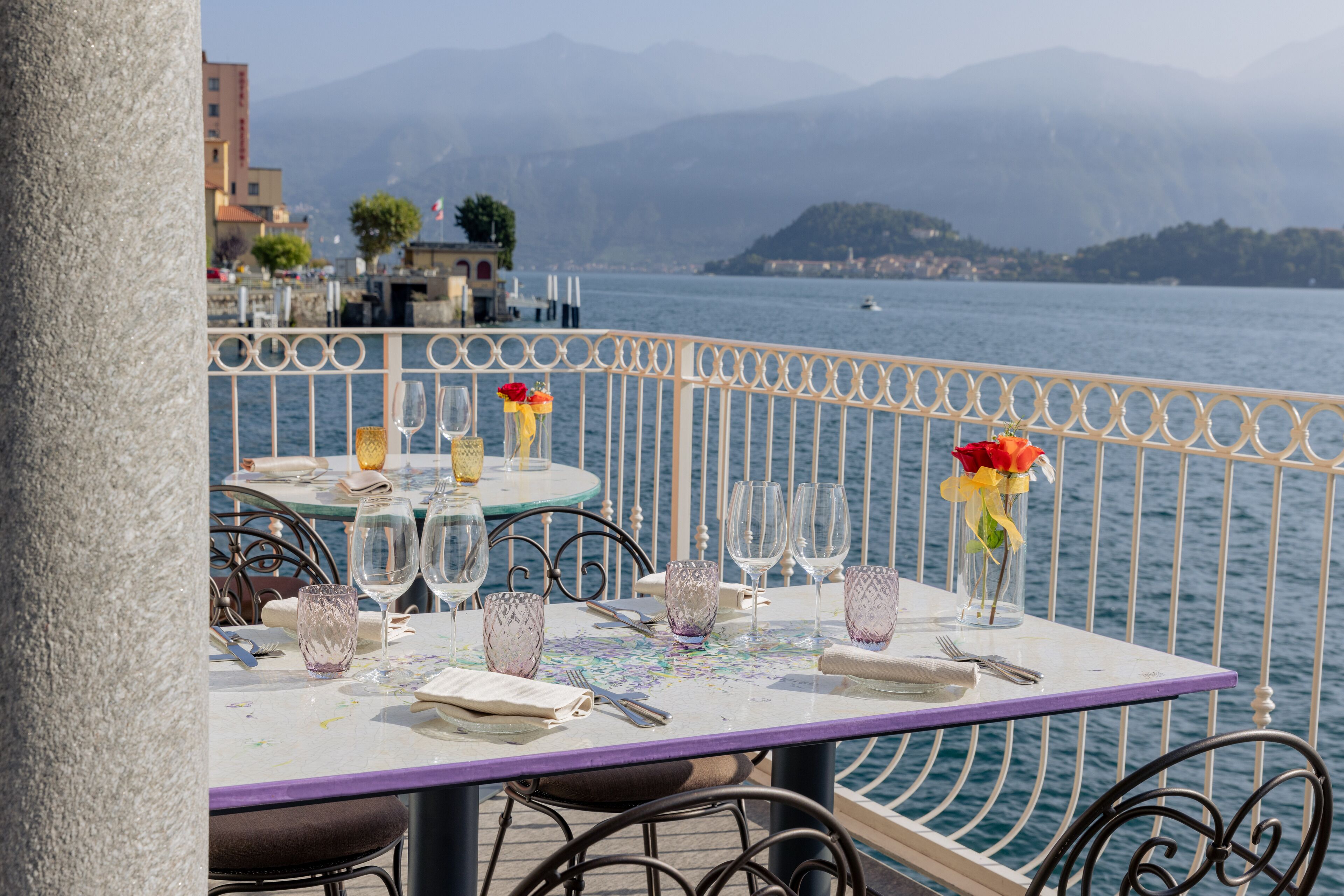 A table set for dining with a view of a lake and mountains in the background.
