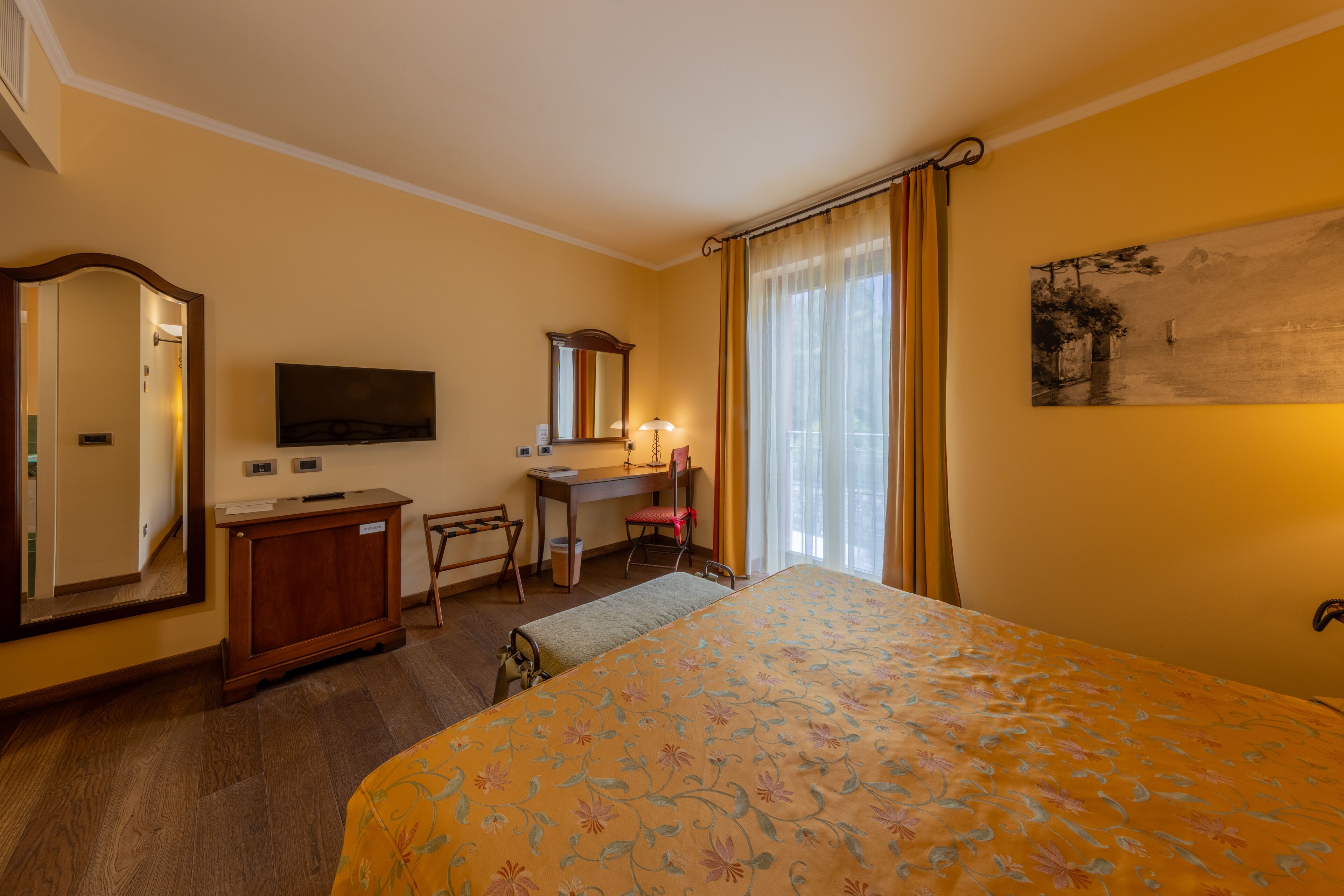 Une chambre d’hôtel équipée d’un lit, d’un bureau, d’une chaise, d’un miroir et d’un téléviseur.
