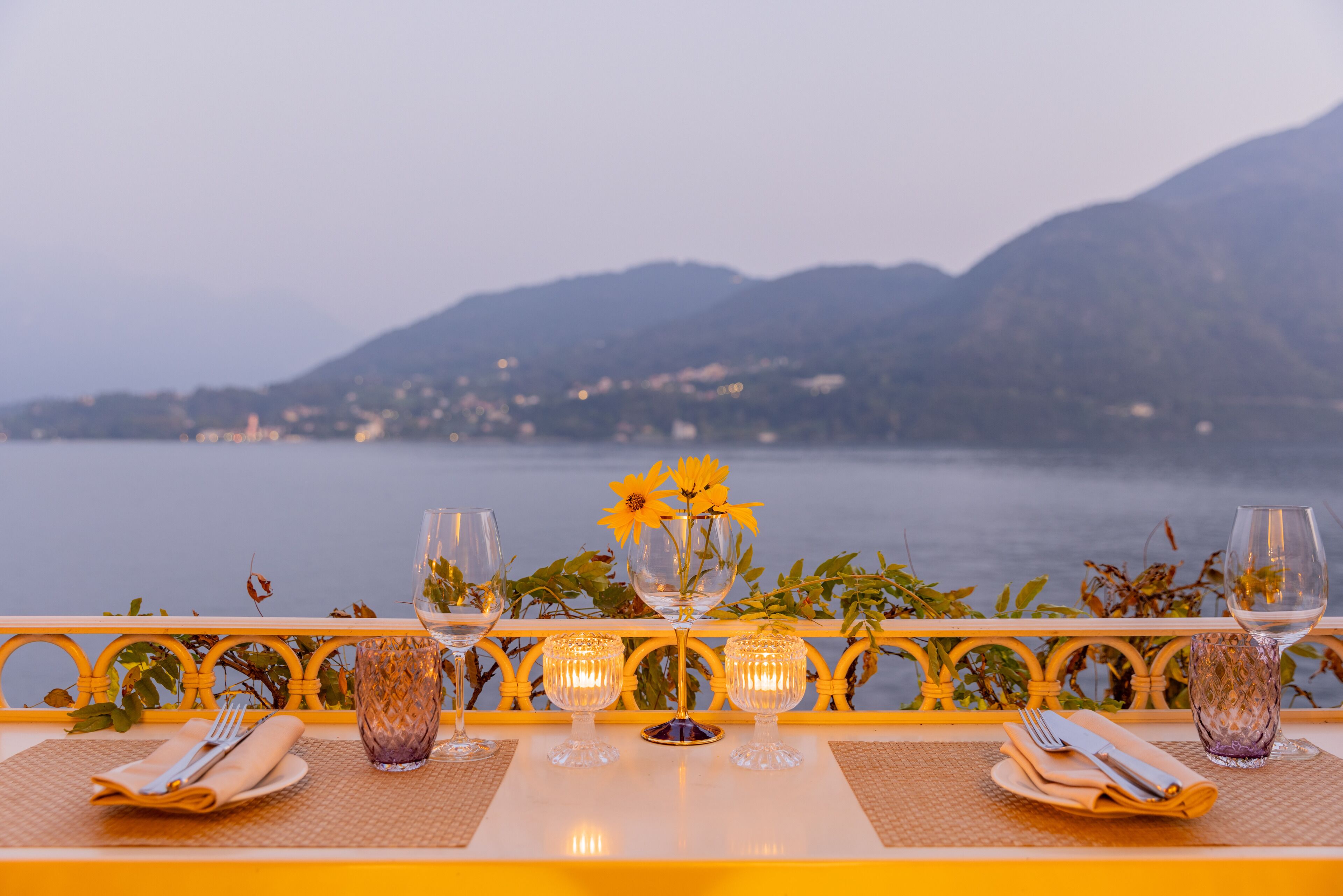 A table set for two with a view of a lake and mountains.