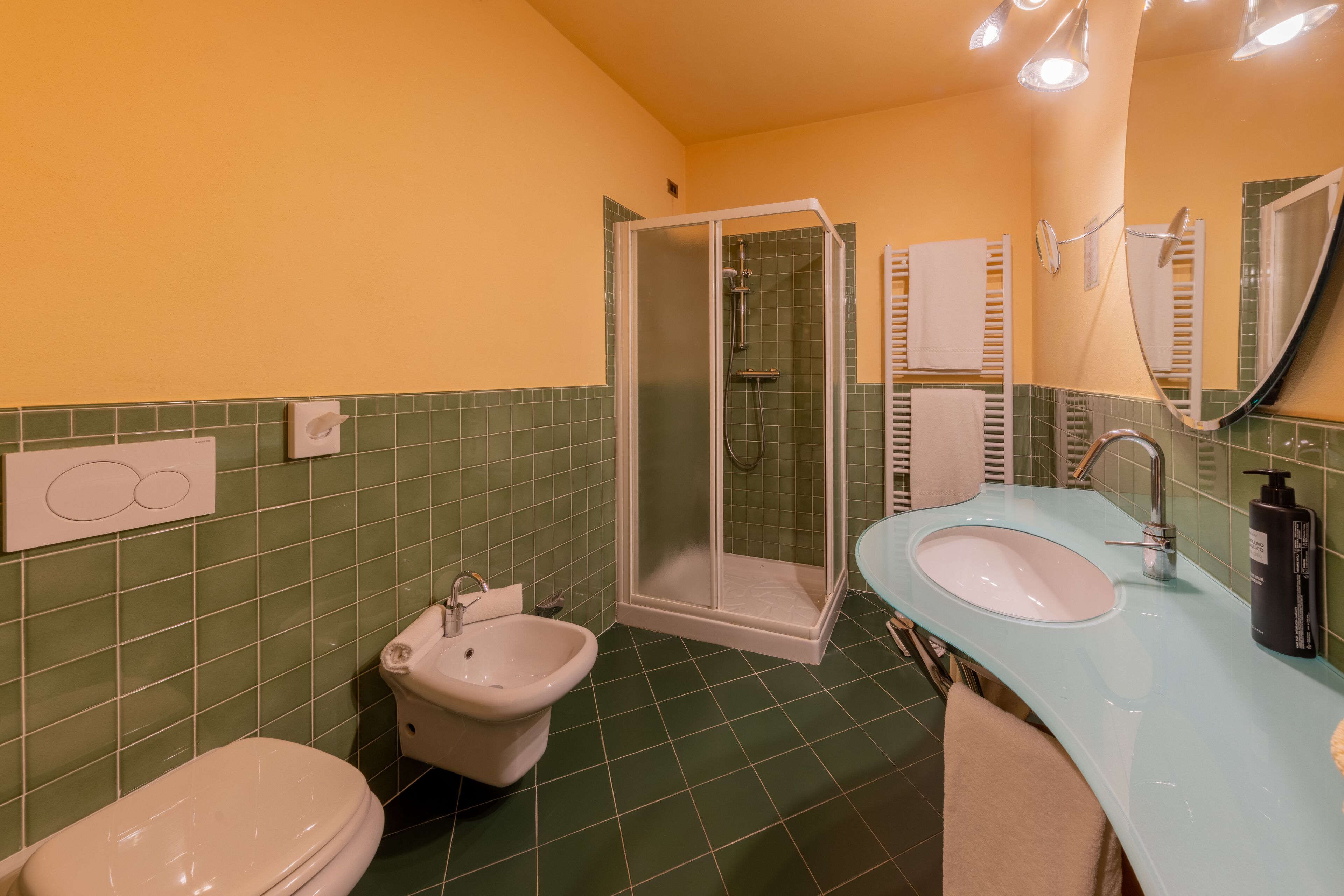 Un baño con cabina de ducha de vidrio, lavamanos con espejo e inodoro.