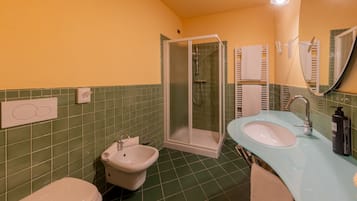 Un baño con cabina de ducha de vidrio, lavamanos con espejo e inodoro.