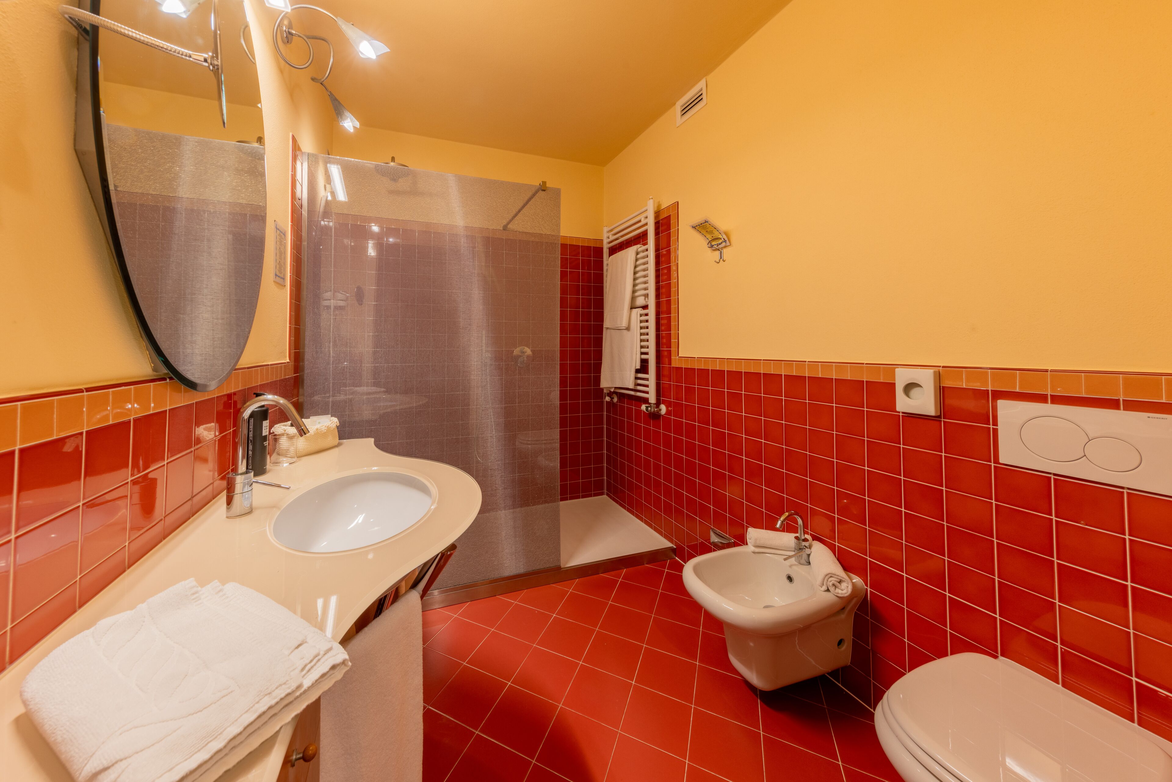 A bathroom with a sink, bidet, toilet, and a shower area.