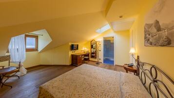 Une chambre à coucher avec un grand lit, un bureau, une chaise, une petite table avec une lampe et une fenêtre avec des rideaux.