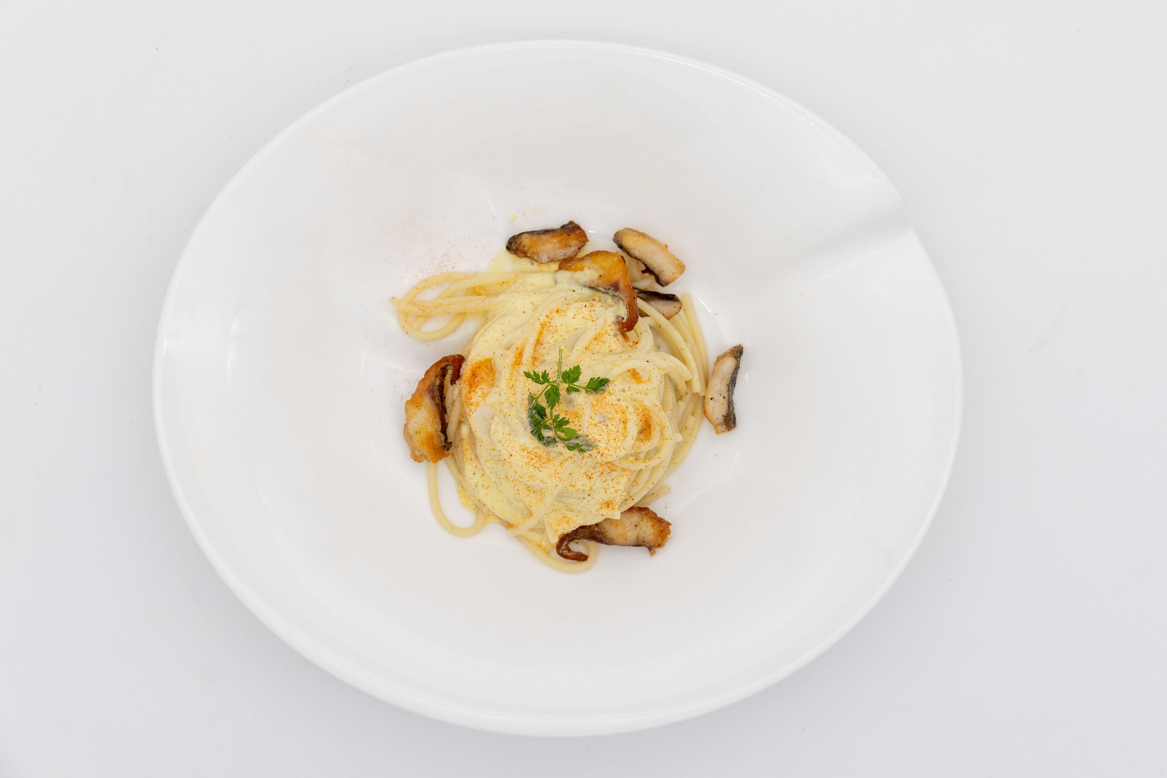 A white plate with pasta, mushrooms, and a garnish.