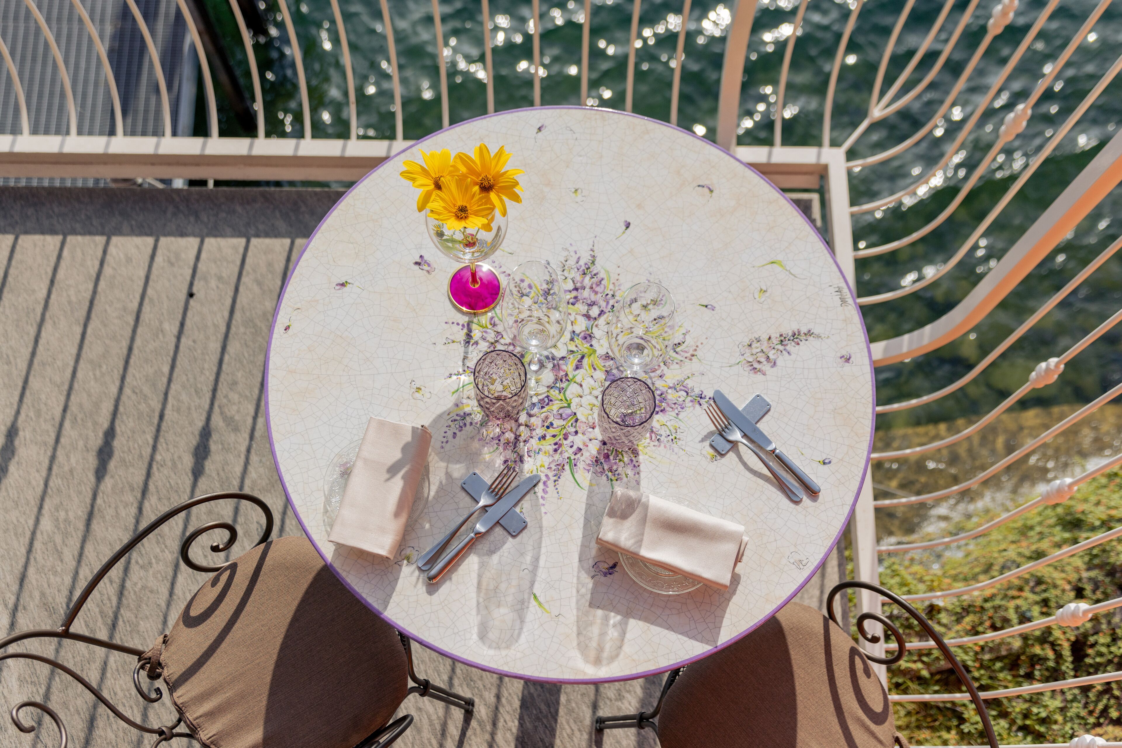 Una mesa redonda con un centro de mesa floral, cubiertos y servilletas.