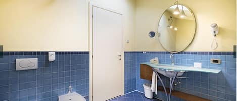 Un baño con inodoro, bidé, lavamanos, espejo y toallero.