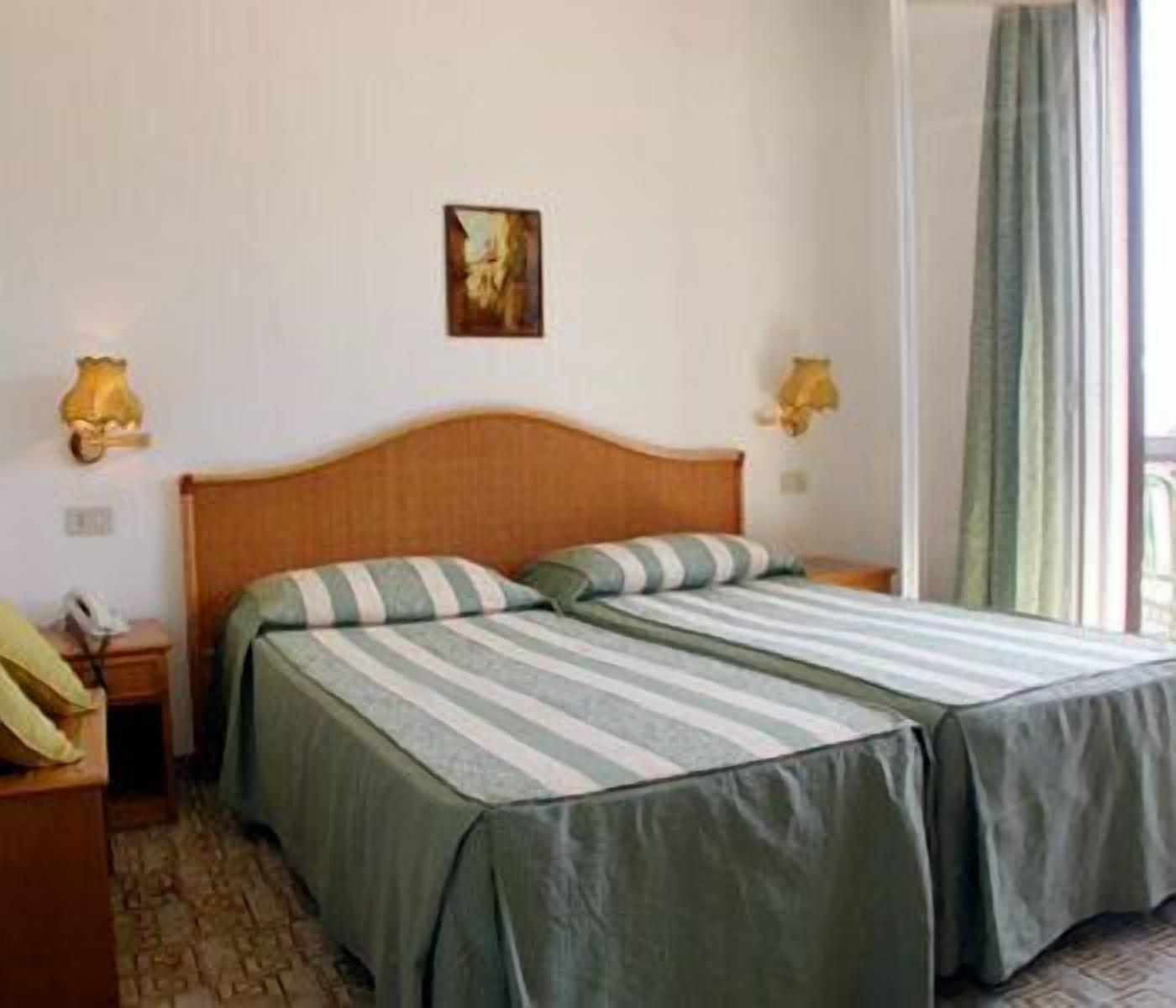 Une chambre d’hôtel avec un lit double, deux tables de chevet, une lampe et un tableau au mur.