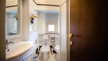 A bathroom with a sink, bidet, toilet, and a mirror.