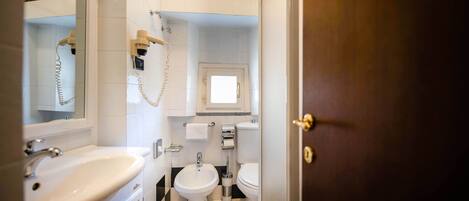 A bathroom with a sink, bidet, toilet, and a mirror.