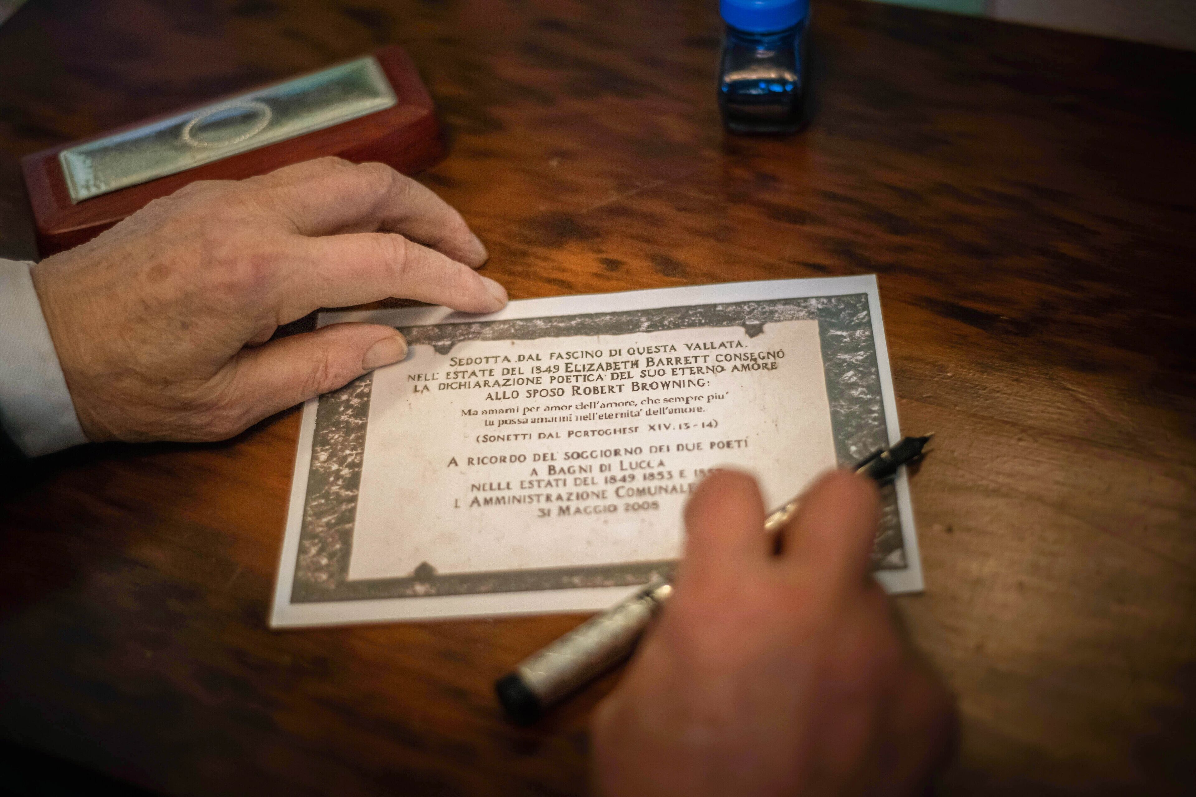 Una persona firmando un documento sobre una mesa de madera.