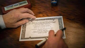 Una persona firmando un documento sobre una mesa de madera.
