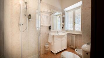 A modern bathroom with a glass-enclosed shower, a white sink, and a toilet.