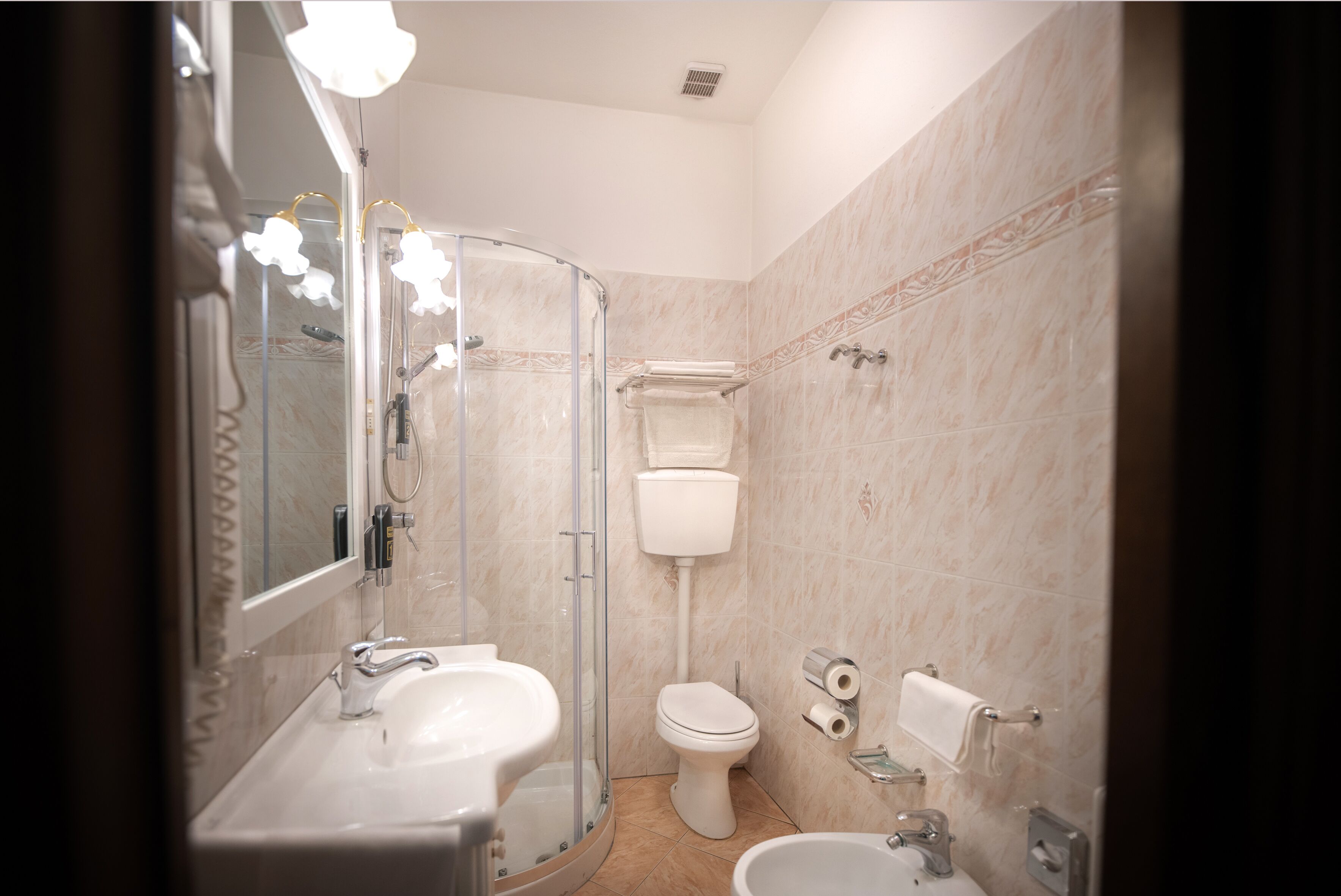Un bany modern amb una dutxa de vidre, un vàter, un lavabo i un bidet.