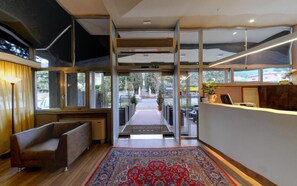 A hotel lobby with a reception desk, seating area, and a view of the outdoor area. - Hotel Ai Ronchi Motor (Brescia)
