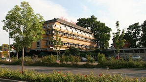 Een hotel met meerdere verdiepingen, een gele gevel en balkons.
