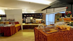 Een hotelontbijtruimte met buffettafels, een koffieapparaat en diverse soorten eten.